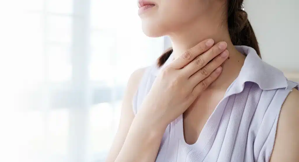 Strep vs sore throat: woman touching neck showing difference between throat pain